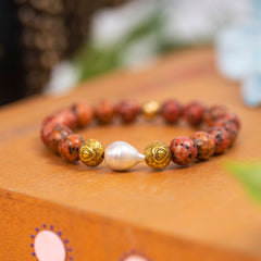  Eykaa Orange Dalmatian And Freshwater Pearl Bracelet Displayed On A Textured Orange Surface.