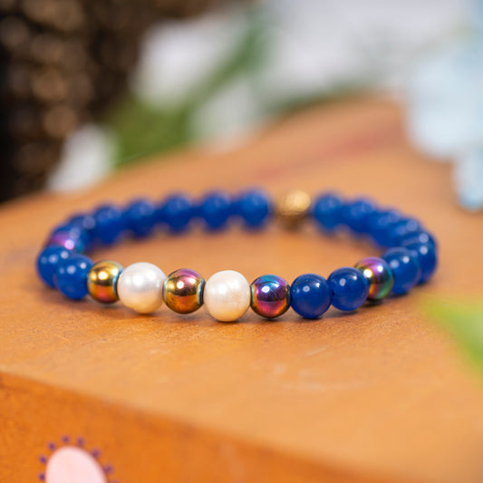 Eykaa Blue Onyx, Rainbow Hematite, And Freshwater Pearl Bracelet Displayed On A Textured Orange Surface.