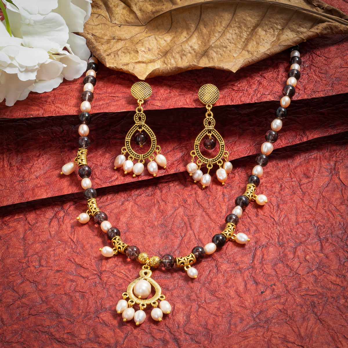 Eykaa Smokey Quartz And Fresh Water Pearl Necklace With Earrings On A Textured Red Background With White Flowers.