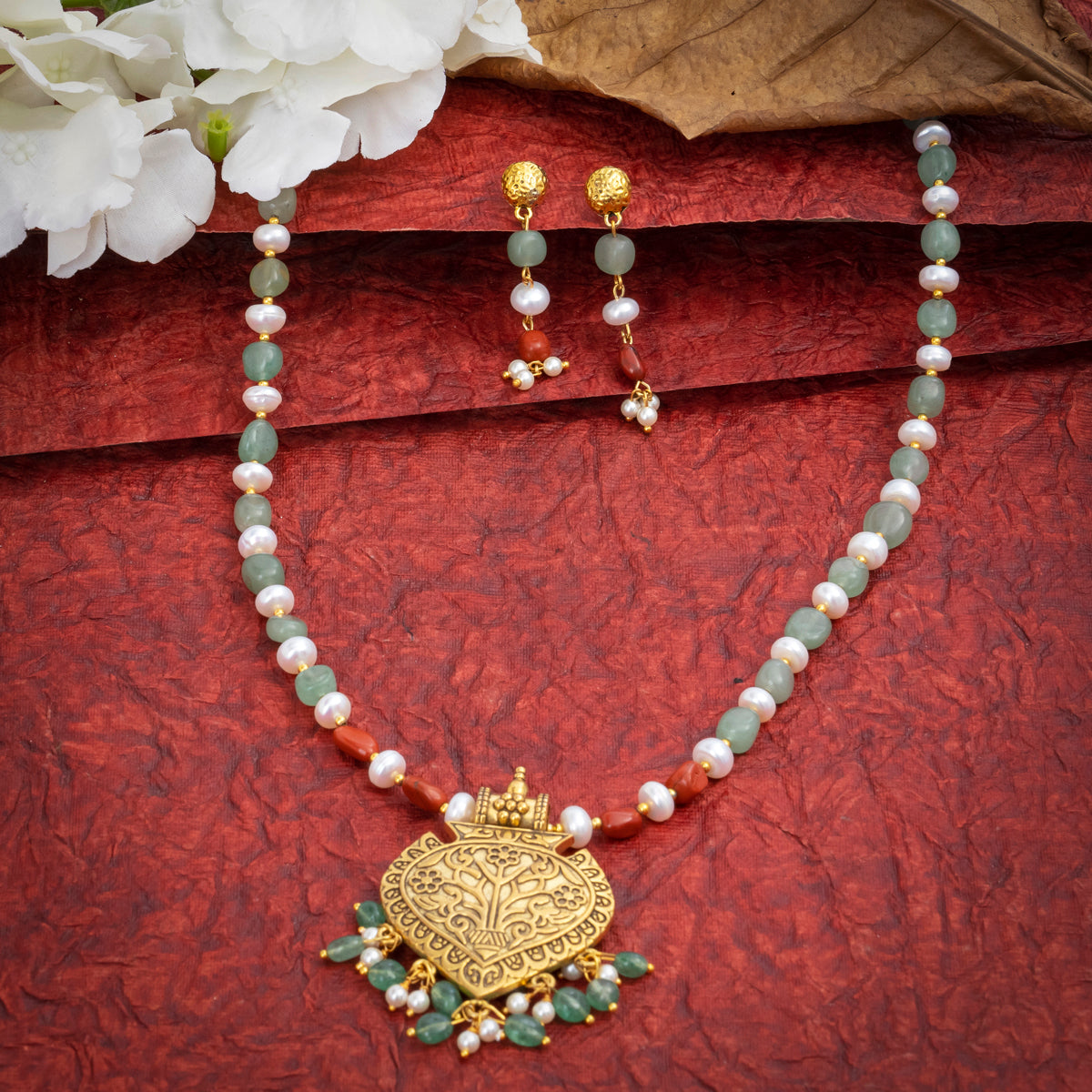   Eykaa Green Aventurine With Freshwater Pearl, Silver Strawberry Quartz, And Shell Pearl With Golden Pendant Necklace With Earrings And Bracelet On A Vibrant Red Surface.