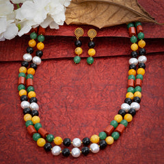 Eykaa Black Onyx, Red Jasper, Green Jade And Yellow Jade With Korean Pearl Ball Necklace With Earrings On A Textured Red Background With White Flowers.