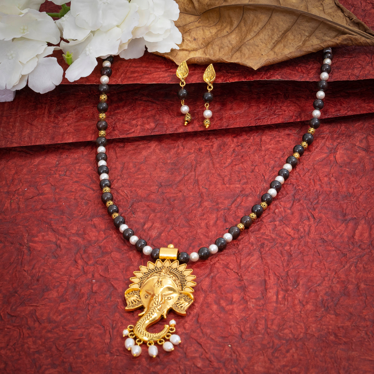 Eykaa Garnet With Fresh Water Pearl And Shell Pearls Necklace And Earring On A Textured Red Background With White Flowers.