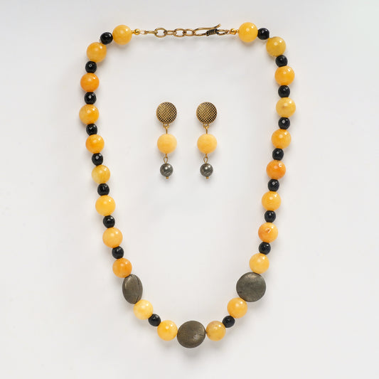 Eykaa yellow jade with pyrite coins and faceted black jade semi precious stone necklace and earrings on white background.