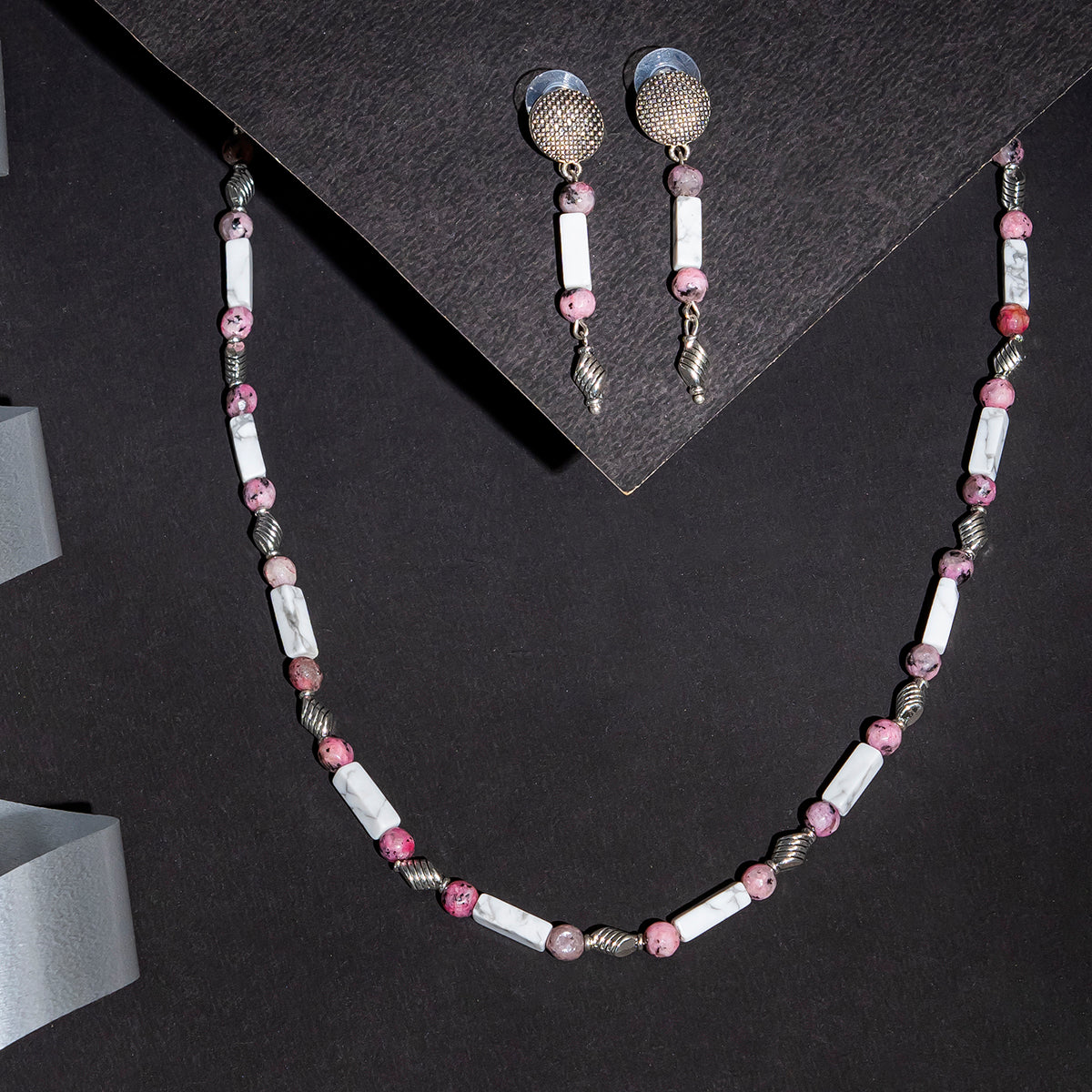 Eykaa white howlite with dalmatian and silver charms semi precious stone necklace and earrings on black background.