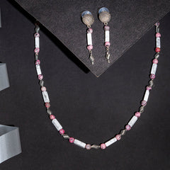 Eykaa white howlite with dalmatian and silver charms semi precious stone necklace and earrings on black background.